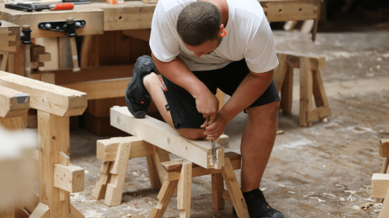 Sich in Ausbildung befindlicher Zimmerer bei der Bearbeitung einer Holzstücks